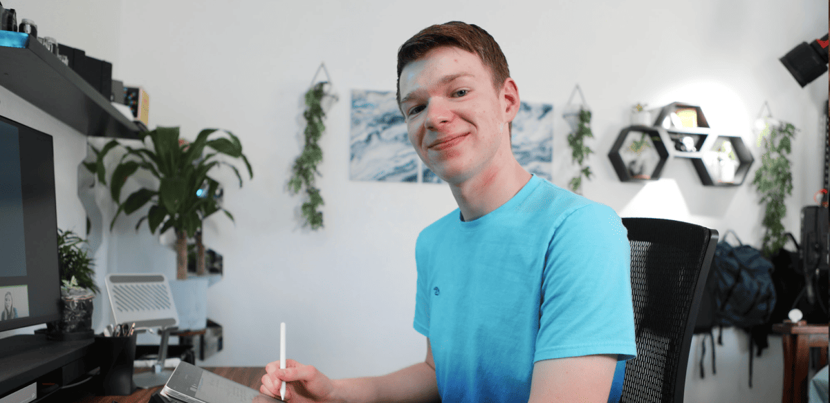 Ein Mann, der an einem Schreibtisch sitzt und mit einem Stift schreibt, während er einen Computer für seine Arbeit oder sein Studium benutzt.