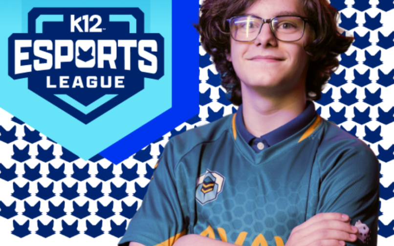 Eine Person in einem blaugrünen E-Sport-Trikot steht mit verschränkten Armen vor einem gemusterten Hintergrund mit sich wiederholenden blauen Fuchs-Symbolen. Links ist ein großes blaues, schildförmiges Logo mit der Aufschrift „K12 Esports League” und einem stilisierten Fuchs-Emblem über dem Text zu sehen.